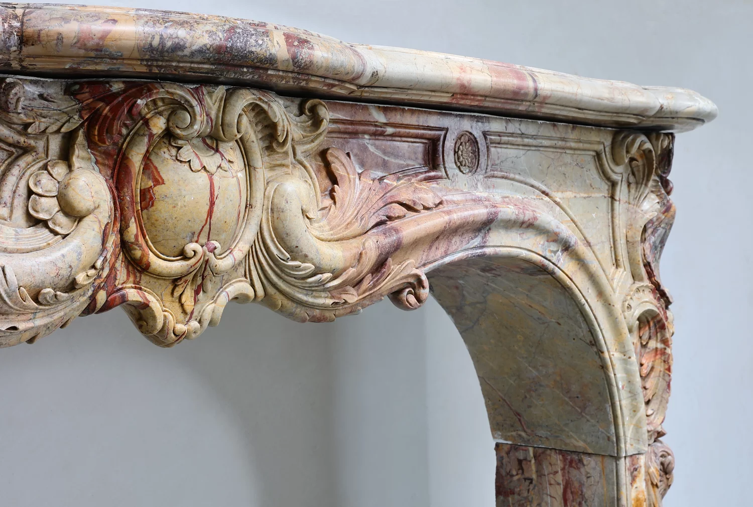 Detail eines antiken Sarrancolin-Marmorkamins, Louis-XV Kaminumrandung mit Bogenöffnung, Muschelwerk, Rocaille-Ornamentik, Blütenrosette und polychromer Marmoraderung